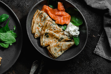 Thin pancakes with herbs, salmon and cream cheese on a plate. crepes