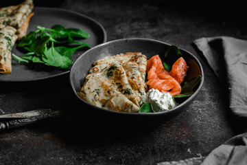 Thin pancakes with herbs, salmon and cream cheese on a plate. crepes