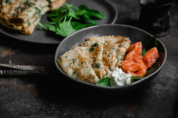 Thin pancakes with herbs, salmon and cream cheese on a plate. crepes