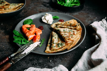 Thin pancakes with herbs, salmon and cream cheese on a plate. crepes