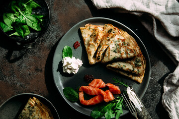 Thin pancakes with herbs, salmon and cream cheese on a plate. crepes