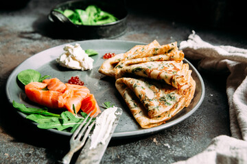 Thin pancakes with herbs, salmon and cream cheese on a plate. crepes