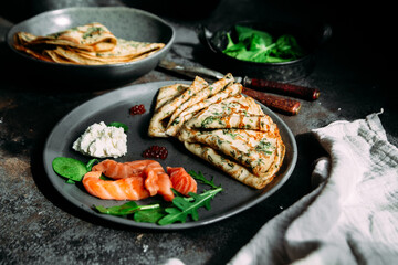 Thin pancakes with herbs, salmon and cream cheese on a plate. crepes
