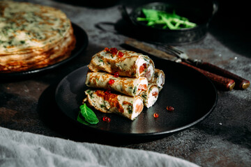 Thin pancakes with herbs, salmon and cream cheese on a plate. crepes