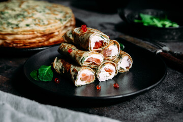 Thin pancakes with herbs, salmon and cream cheese on a plate. crepes