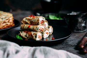 Thin pancakes with herbs, salmon and cream cheese on a plate. crepes