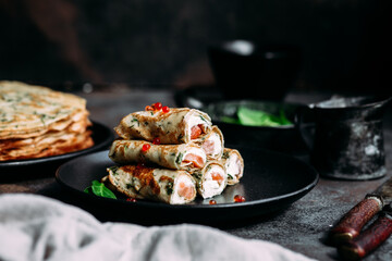 Thin pancakes with herbs, salmon and cream cheese on a plate. crepes