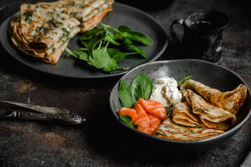 Thin pancakes with herbs, salmon and cream cheese on a plate. crepes