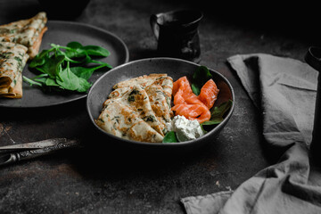 Thin pancakes with herbs, salmon and cream cheese on a plate. crepes