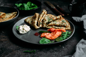 Thin pancakes with herbs, salmon and cream cheese on a plate. crepes