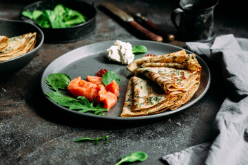 Thin pancakes with herbs, salmon and cream cheese on a plate. crepes