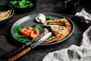 Thin pancakes with herbs, salmon and cream cheese on a plate. crepes