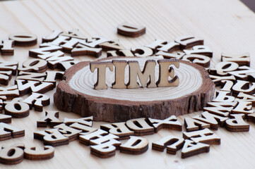 TIME written with wooden letters decorated on pine wooden chip decoration. Time is precious.