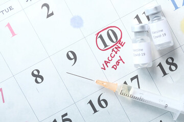 Fototapeta premium coronavirus vaccine and syringe on calendar background