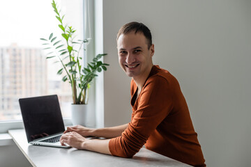 Happy young man, smiling, as he works on his laptop