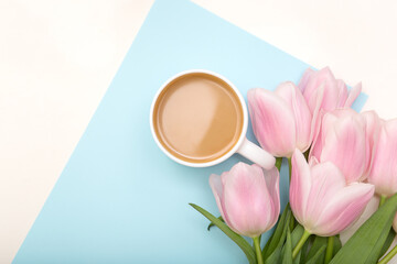 Morning cup of coffee and beautiful tulips flowers on light pastel background