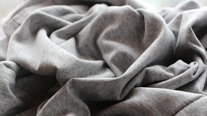 Fototapeta premium gray knit fabric crumpled with casual folds forms a textured solid background, soft cotton fabric with a wavy texture as a monochrome minimalist backdrop