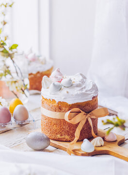 Traditional ukrainian easter cake with white swiss meringue. New cruffin cake trend 2024. Spring cherry blossom and colorful painted eggs. Person decorates cake with hand. Free copy space