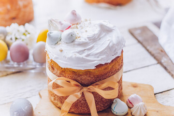 Traditional ukrainian easter cake with white swiss meringue. New cruffin cake trend 2021. Spring cherry blossom and colorful painted eggs. Person decorates cake with hand. Free copy space