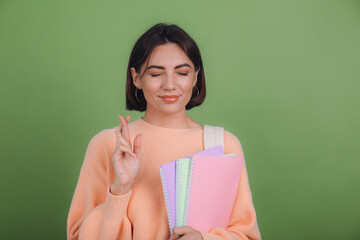 Young woman in casual peach sweater and backpack isolated on green olive color background wait for...