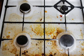Top view of a very dirty white gas stove with yellow streaks and greasy spots