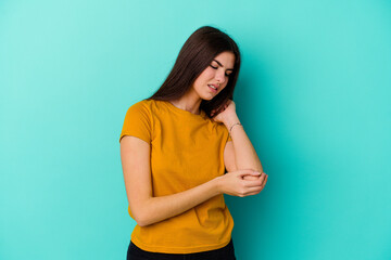 Obraz premium Young caucasian woman isolated on blue background massaging elbow, suffering after a bad movement.