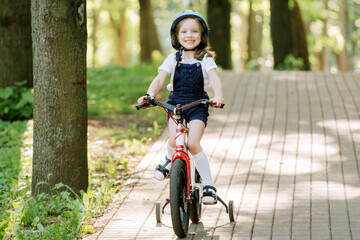 Naklejka premium Cheerful smiling girl in helmet on bicycle.