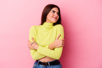 Young caucasian woman isolated on pink background hugs, smiling carefree and happy.