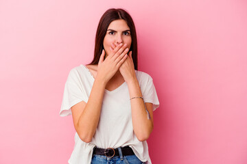 Young caucasian woman isolated on pink background shocked covering mouth with hands.