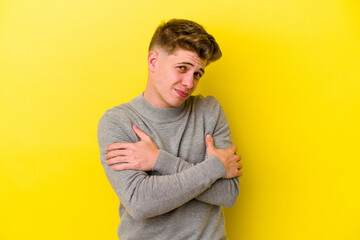 Young caucasian man isolated on yellow background hugs, smiling carefree and happy.