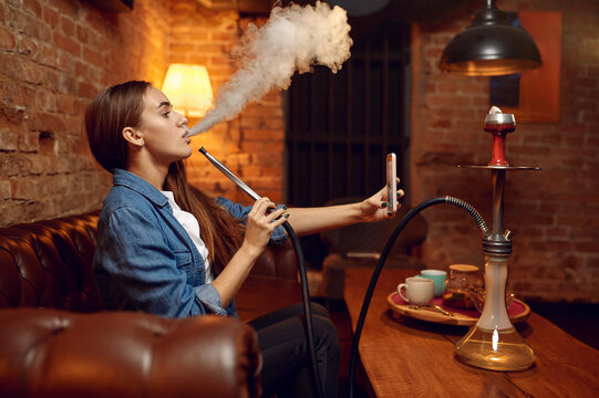Young woman makes selfie with hookah in bar