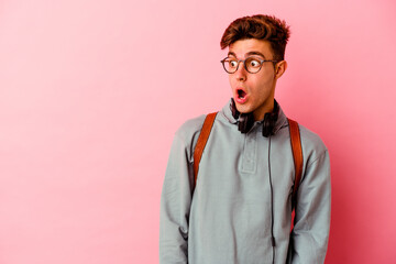 Young student man isolated on pink background being shocked because of something she has seen.