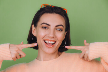 Young stylish woman in casual peach sweater and orange glasses isolated on green olive background...