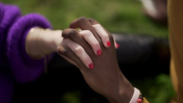Ethnically diverse couple holding hands close-up. Mixed race woman and black man showing love and affection