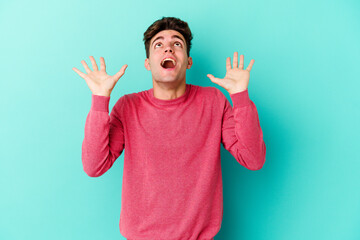 Young caucasian man isolated on blue background screaming to the sky, looking up, frustrated.