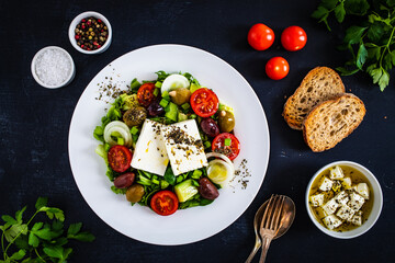 Fresh Greek salad - feta cheese, tomatoes, cucumber, lettuce, black olives and onion on wooden table
