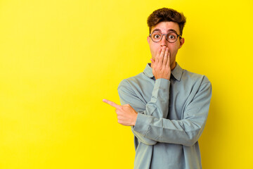 Young caucasian man isolated on yellow background pointing to the side
