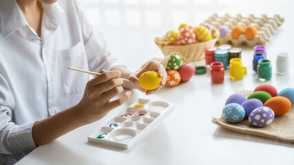 Happy Asian woman painting eggs for Eastertime at home. Family preparing for Easter.
