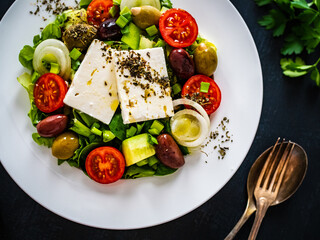 Fresh Greek salad - feta cheese, tomatoes, cucumber, lettuce, black olives and onion on wooden...