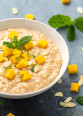 Rice pudding with cinnamon and mango in white bowl