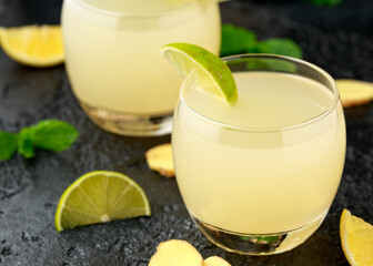 Ginger and lemon beer sparkling fizzy drink in glasses with lime wedges on the side