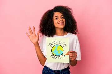 Young african american curly woman holding a planet message on a placard smiling cheerful showing number five with fingers.