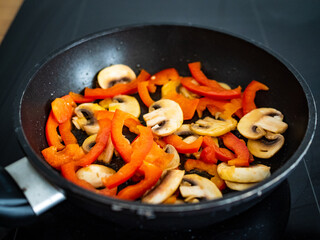 White mushrooms and bell pepper frying in pan
