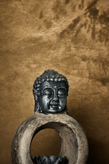 Small Buddha sculpture on textured bronze background