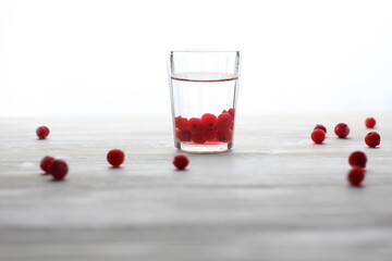 Glass with vodka and cranberries on white background