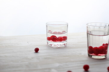 Short glass with vodka and cranberries on white background