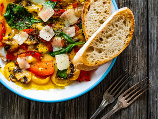 Delicious breakfast - scrambled eggs with onion, bell pepper, parmesan and mix of young vegetable leaves on wooden table