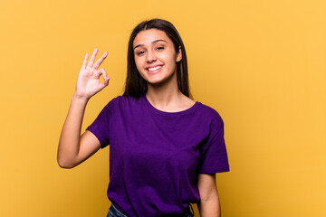 Young Indian woman isolated on yellow background cheerful and confident showing ok gesture.