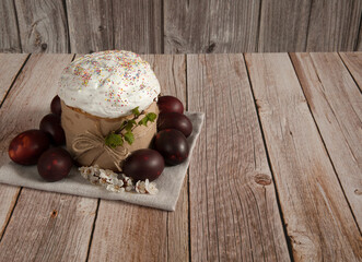 Easter composition. A blooming apricot branch, painted eggs and a glazed easter cake decorated with sugar sprinkles on a wooden background. Happy Easter Holidays. Free space.