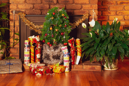 Vintage house decorated with small Christmas tree placed in front of a fireplace. The gifts are arranged on the floor. Suitable to illustrate modest Christmas festivity without depicting people.